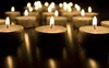 A close-up shot of multiple lit tea light candles on a dark surface. Náhled obrázku produktu