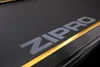 A close-up shot of a black surface with a carbon fiber texture, featuring the gray 'ZIPRO' logo and a thin gold stripe. Podgląd zdjęcia produktu