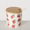 A ceramic jar with a strawberry pattern and a wooden lid with a spoon slot. Produktbild-Vorschau