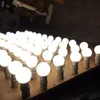 A collection of LED light bulbs arranged in rows on a wooden surface. Produktbild-Vorschau
