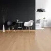 A modern living room with a black accent wall, two chairs, a small table, and a sofa in the background. Produktbild-Vorschau