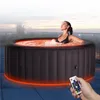 A woman relaxing in an illuminated hot tub on a rooftop at dusk. Produktbild-Vorschau