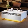 A modern white coffee table with LED lighting is placed in a living room setting, next to a dark leather sofa. Náhled obrázku produktu