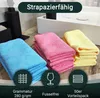 Three stacks of colorful microfiber cleaning cloths on a wooden surface, with a sink and faucet in the background. Produktbild-Vorschau
