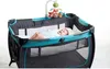 A baby is lying in a playpen with a mobile above it. Voir les images du produit