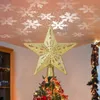 A golden star tree topper projects snowflake patterns onto a ceiling, with a decorated Christmas tree visible below. Produktbild-Vorschau