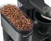 A close-up view of a coffee maker's bean hopper filled with coffee beans, and part of the brewing mechanism. Produktbild-Vorschau