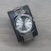 A silver Invicta watch is displayed on a dark gray watch stand, placed on a wooden surface. Náhľad obrázku produktu