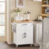 A white kitchen cart with a wooden top is shown in a kitchen setting, next to a doorway and a stove. Podgląd zdjęcia produktu