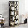 A tall, narrow bookshelf with black marble-effect sides and gold metal frame, filled with books and decorative items, placed against a textured white wall. Produktbild-Vorschau