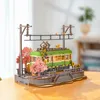 A detailed 3D wooden model of a tram station with cherry blossom trees, set on a wooden table. Produktbild-Vorschau