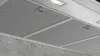 A close-up view of a stainless steel range hood with integrated lighting and a concrete wall. Voir les images du produit