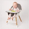 A baby sitting in a high chair with food on the tray. Voir les images du produit