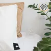 A close-up shot of pillows on a bed with a plant and a wall outlet visible. Produktbild-Vorschau