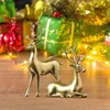 Two golden reindeer figurines are displayed on a wooden surface with Christmas gifts and lights in the background. Produktbild-Vorschau
