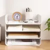 A white four-tier desk organizer filled with notebooks, a calculator, glasses, and pens. Produktbild-Vorschau