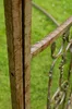 A close-up view of a rusty metal gate or fence post with a green grassy background. Anteprima dell’immagine prodotto