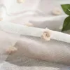 A close-up view of a white sheer curtain with small, fluffy pom-pom embellishments. Produktbild-Vorschau