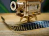 A close-up of a wooden model film projector with a strip of film in the foreground. Produktbild-Vorschau