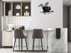 A modern kitchen with a coffee-themed wall clock and bar stools. Voir les images du produit