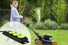 A woman is mowing her lawn with a lawnmower, and a close-up of a power strip is overlaid on the image. Produktbild-Vorschau