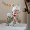 A young boy wearing a birthday crown is decorating a toy birthday cake with candles. Podgląd zdjęcia produktu