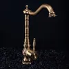 A vintage-style bronze faucet sits on a bed of black gravel against a black background. Podgląd zdjęcia produktu
