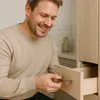 A man is opening a wooden drawer with a silver handle. Produktbild-Vorschau
