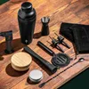 A collection of black barware tools arranged on a wooden surface. Voir les images du produit