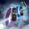 Three smartwatches in different colors are displayed against a smoky, graffiti-covered background. Voir les images du produit