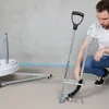 A man is kneeling on the floor next to a tool for installing underfloor heating pipes. Náhľad obrázku produktu