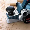 A close-up of a Bosch electric planer on a surface covered with wood shavings. Voir les images du produit
