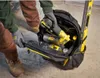 A person wearing work clothes and gloves is putting tools into a black and yellow tool bag. Voir les images du produit