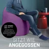 A person sits on a purple beanbag chair in a room with a red side table. Anteprima dell’immagine prodotto