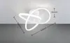 A white LED ceiling light with a modern, abstract design is shown mounted on a white ceiling against a gray background. Dimensions are indicated with measurement lines and text. Podgląd zdjęcia produktu