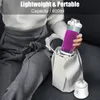 A person is holding a portable blender with a purple smoothie inside, placing it into a white tote bag. Produktbild-Vorschau