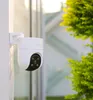 A white dome security camera is mounted on a white pole, with green foliage in the background. Anteprima dell’immagine prodotto