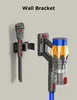 Two wall brackets for a cordless vacuum cleaner are shown mounted on a light gray wall. Produktbild-Vorschau