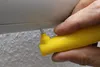 A hand holding a yellow tool is shown pressing a small metal rivet into a gray surface. Produktbild-Vorschau