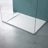 A modern white shower tray with a linear drain, framed by glass panels and set against a teal wall and concrete floor. Produktbild-Vorschau
