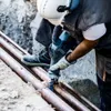 A construction worker is using a jackhammer to break apart old pipes. Voir les images du produit