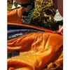 A close-up view of a person's hands zipping up an orange sleeping bag. Anteprima dell’immagine prodotto