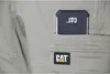 A close-up of a pair of khaki work pants with a black object in the pocket. Produktbild-Vorschau