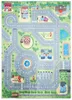 A colorful play mat depicting a city street scene with various buildings, a playground, a carousel, a fountain, a sports field, and a train track. Produktbild-Vorschau