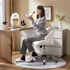 A woman applying makeup at a vanity table. Produktbild-Vorschau