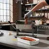 A person's hand wearing a glove is placing a sausage into a slicer in a kitchen setting. Anteprima dell’immagine prodotto