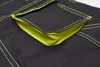 A close-up view of a black garment with bright yellow stitching and lining, focusing on a pocket. Produktbild-Vorschau