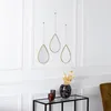 Three teardrop-shaped mirrors with gold frames hang on a white paneled wall above a glass-top console table with decorative items. Produktbild-Vorschau