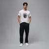 A man is standing in front of a plain gray background, wearing a white t-shirt with a graphic of a basketball and black cargo pants. Náhled obrázku produktu