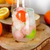 A close-up of a glass filled with ice cubes and a drink, with fruit slices in the background. Voir les images du produit
